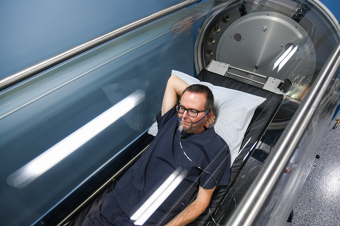 Patient waering an oxygen mask relaxing inside a hyperbaric oxygen chamber